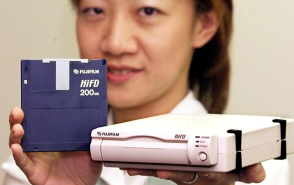 Người phụ nữ cầm một ổ đĩa mềm Fujifilm 200MB dung lượng 3,5' và ổ đĩa mềm mới tại văn phòng công ty ở Tokyo, ngày 28/01/2000.